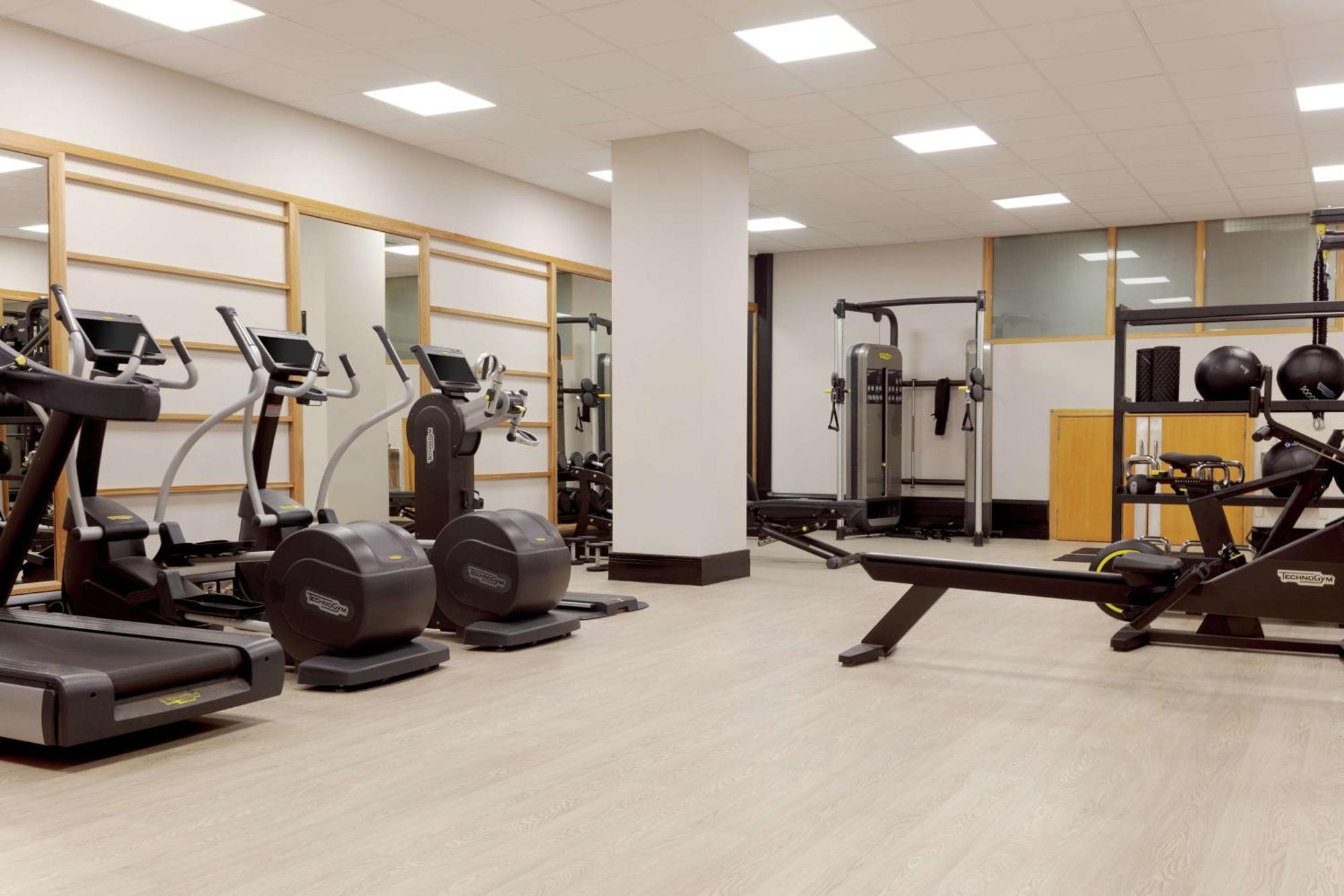 Hilton Belfast Ξενοδοχείο Εξωτερικό φωτογραφία The photo shows a gym or fitness area. It features several exercise machines, including treadmills and elliptical machines. There's also a rowing machine and a multi-station strength training equipment. The space is well-lit with overhead lights and 